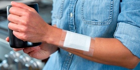 Ein Universal-Pflaster, das einen Verband auf der Hand einer Person fixiert
