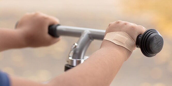 Eine Hand an einem Fahrradlenker mit einem Nexcare™ DUO-Pflaster
