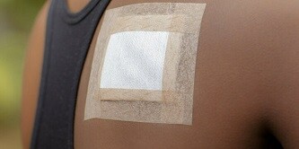 Eine Frau mit einem Verband und Fixierpflaster auf dem Rücken
