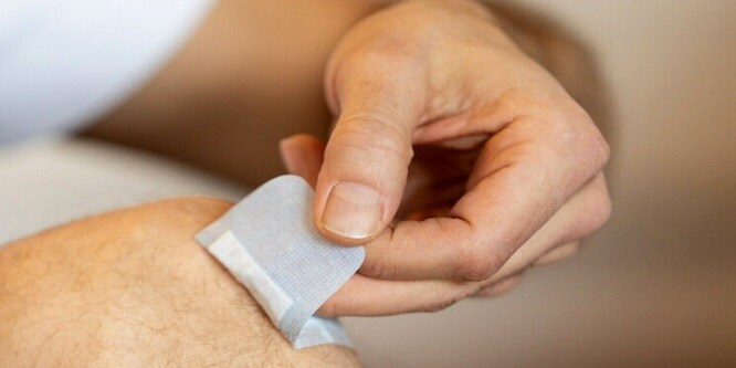 Ein Mann zieht ein Nexcare Pflaster ab
