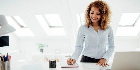 Eine Frau schreibt in einem Büro Notizen
