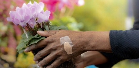 Eine Frau pflückt Blumen mit einem wasserfesten Pflaster auf der Hand
