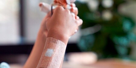 Die Hand einer Person mit einem Pflaster für empfindliche Haut
